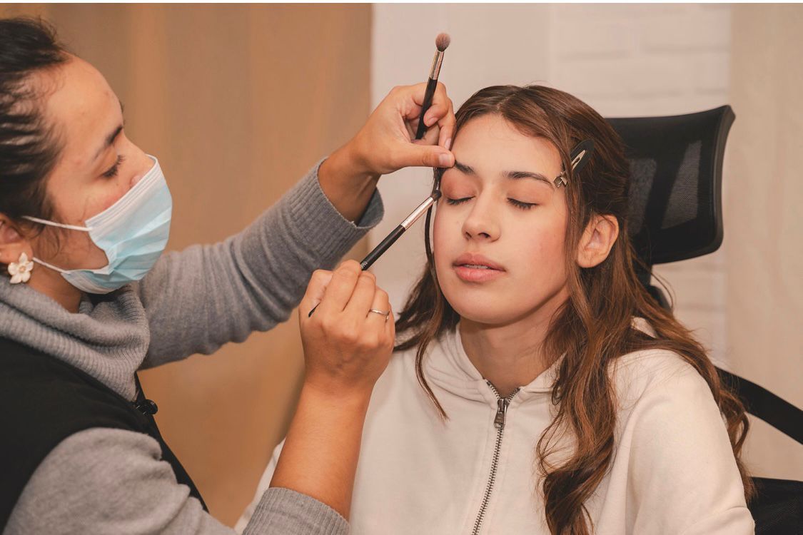 Mujer relajándose en una camilla de masaje, envuelta en una toalla blanca, con flores y una vela cerca.