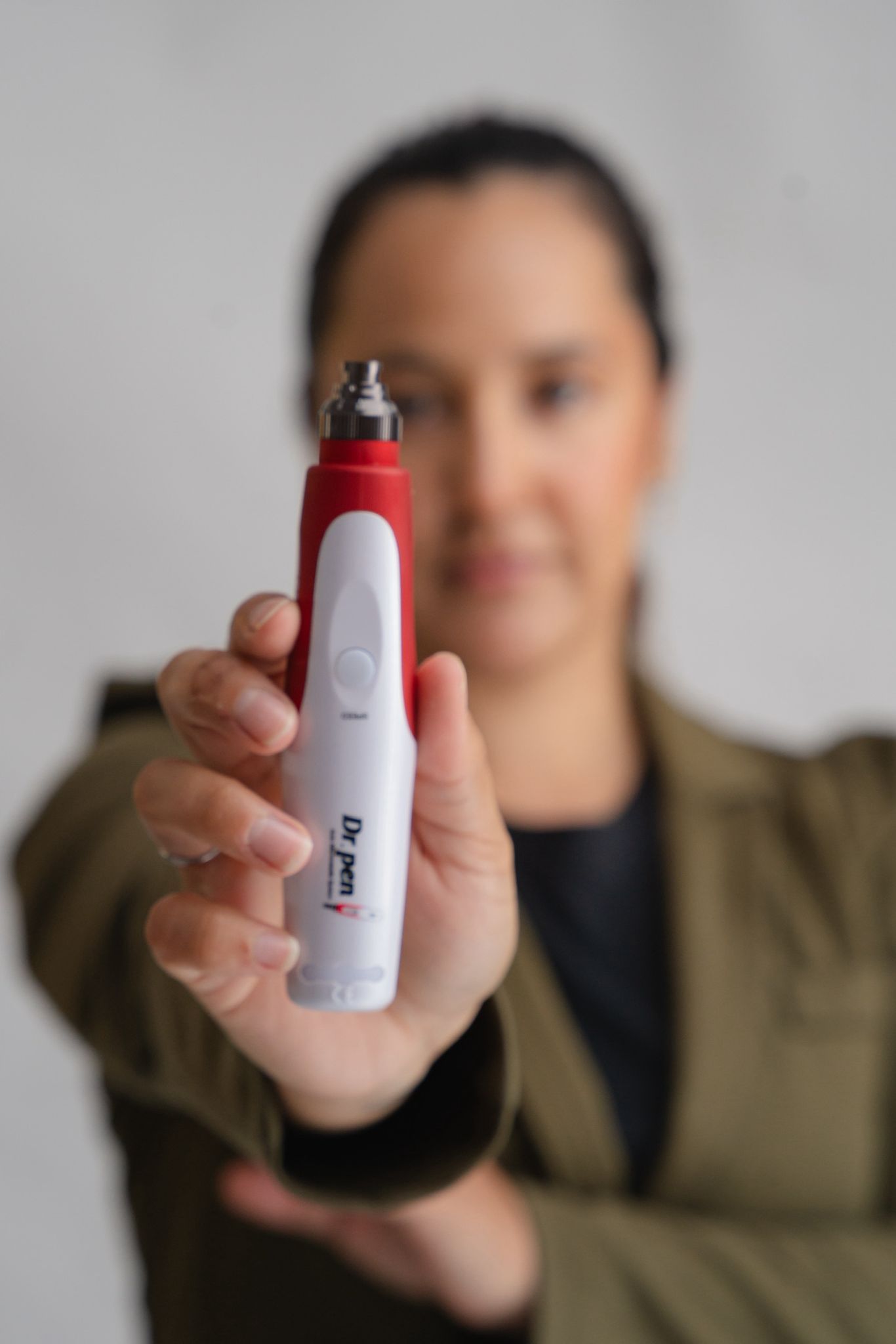 Mujer sosteniendo un dispositivo rojo y blanco, enfoque en el dispositivo, fondo borroso.