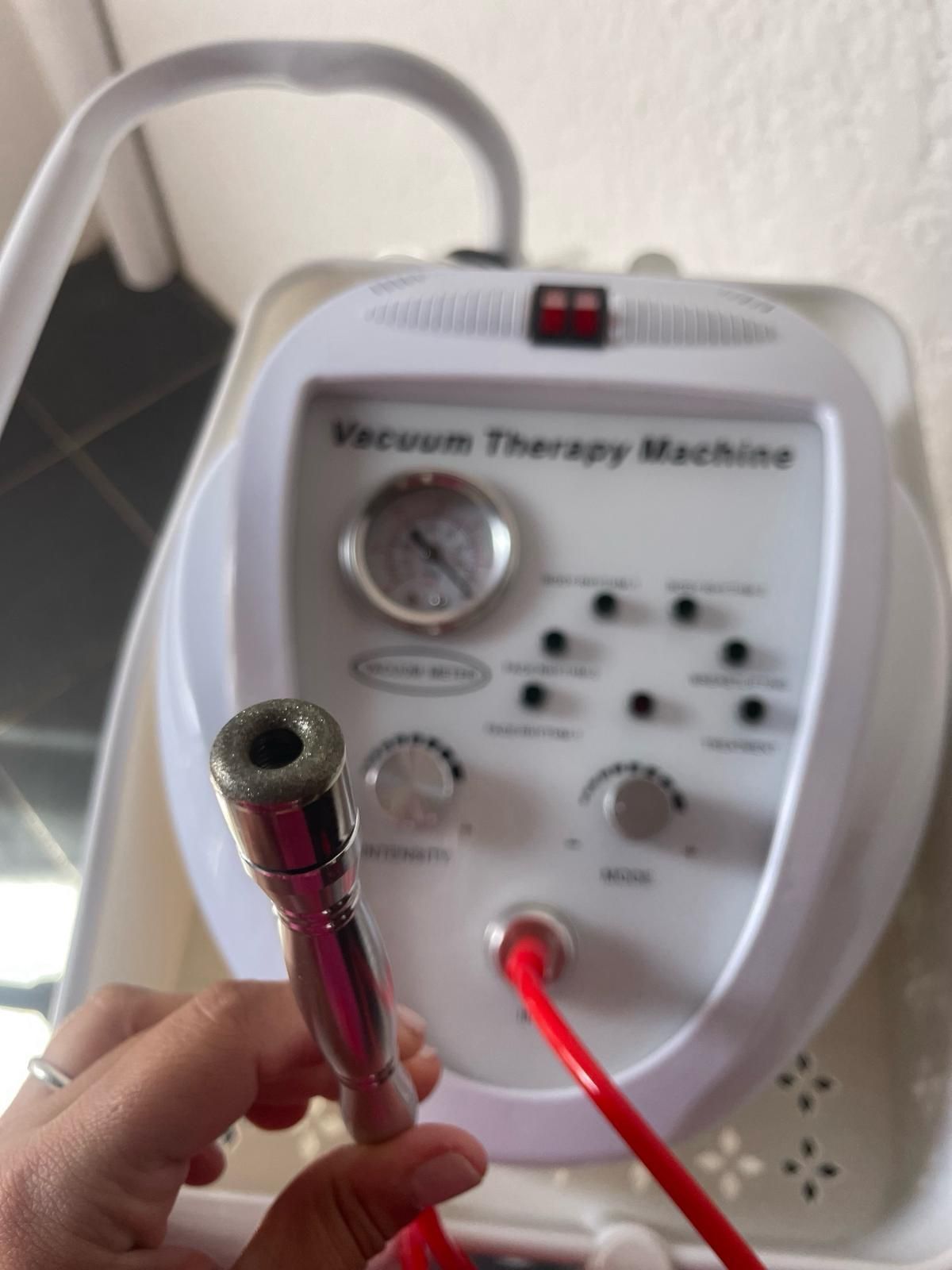 Persona sosteniendo una varita exfoliante de piel con punta de diamante; máquina de terapia de vacío en el fondo.