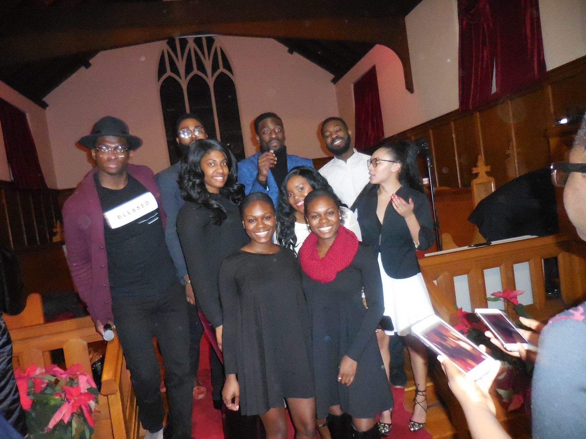 A group of people posing for a photo inside a dimly lit church with wooden pews and arches.