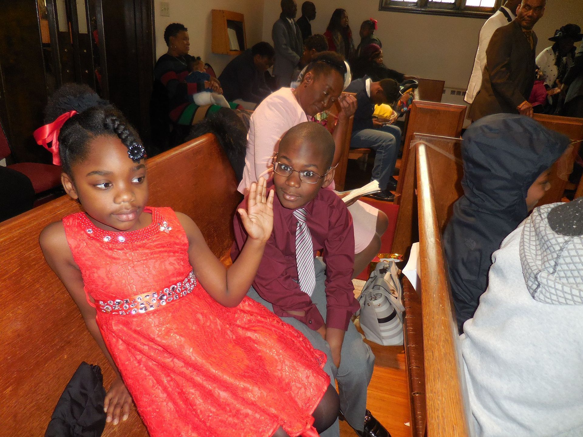 Children in formal attire sitting on wooden pews inside a church.