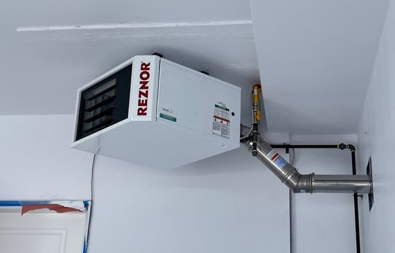 A garage heater installed by Level Up is hanging from the ceiling of a garage