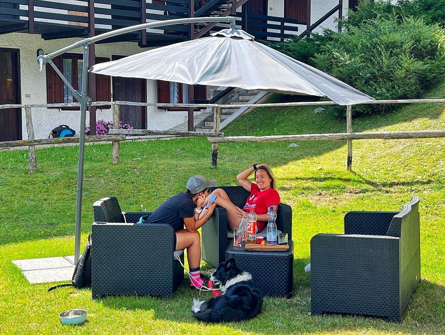 Due persone sono sedute sotto un ombrellone sull'erba.