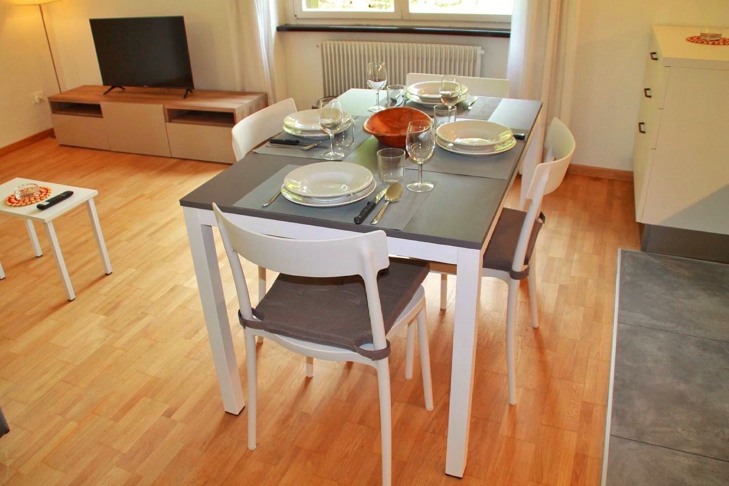 Un soggiorno con tavolo, sedie e televisione