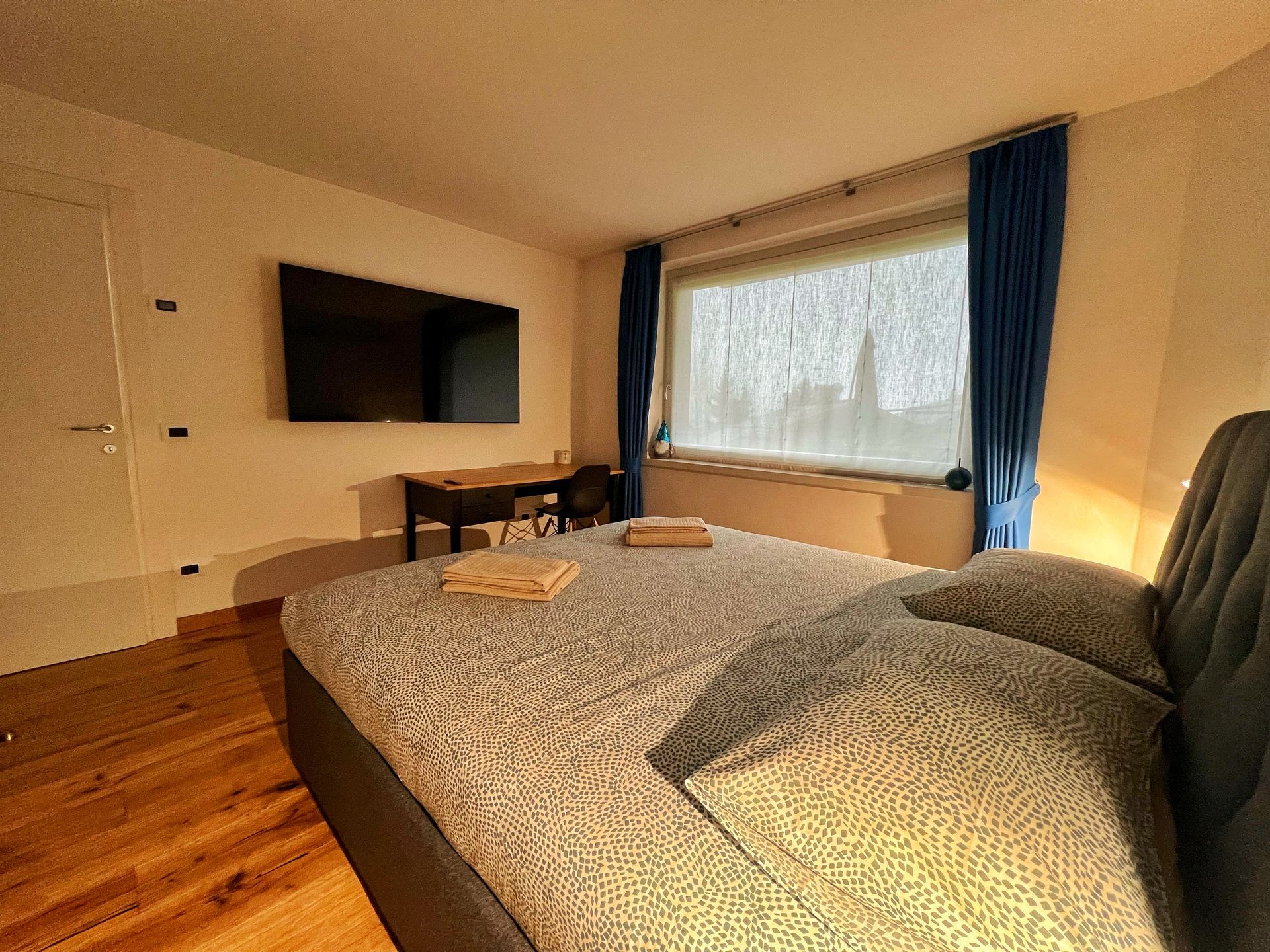 Una camera da letto con un letto grande e una TV a schermo piatto sulla parete.