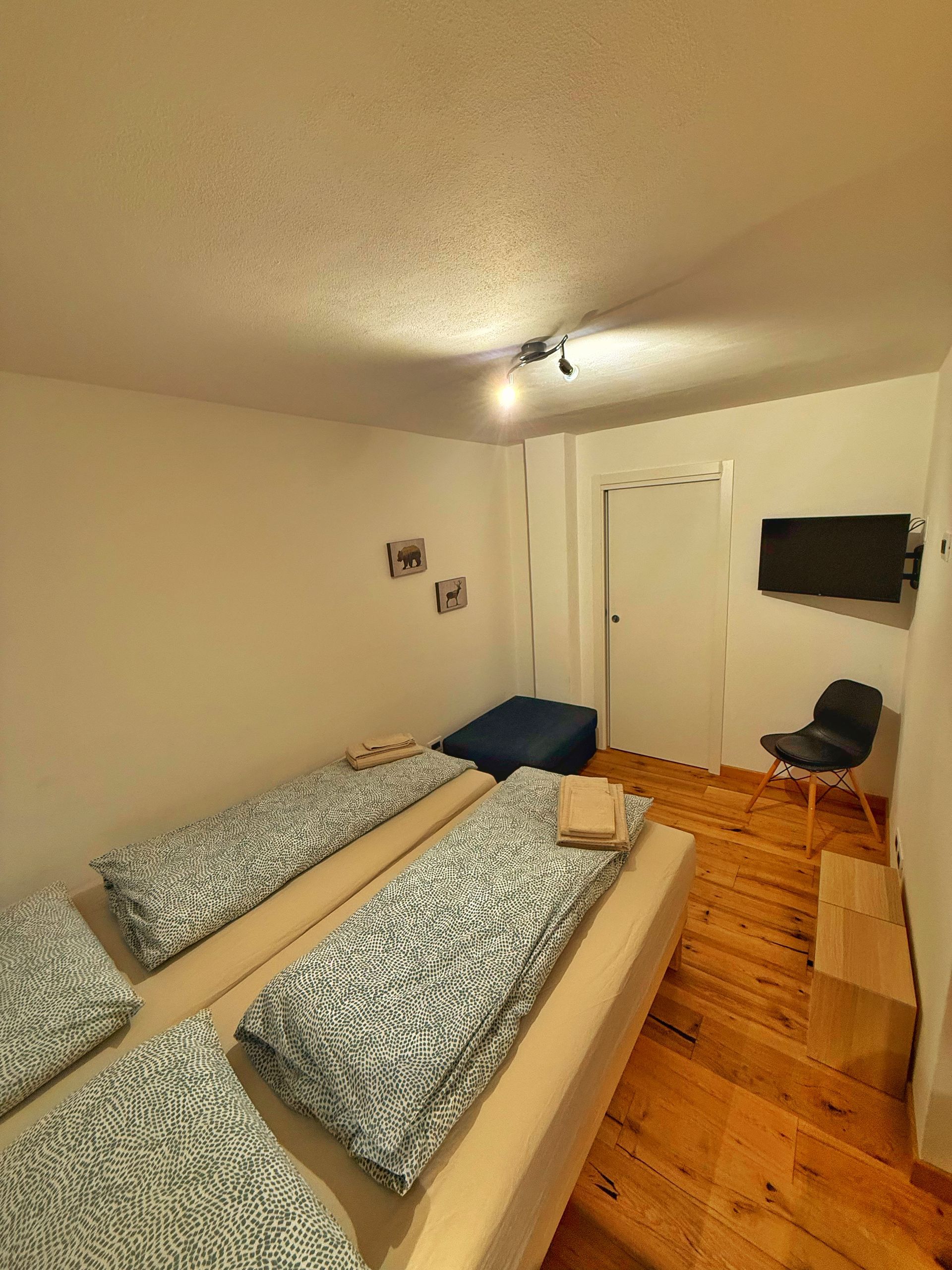 Una camera da letto con due letti e una tv a schermo piatto sulla parete.