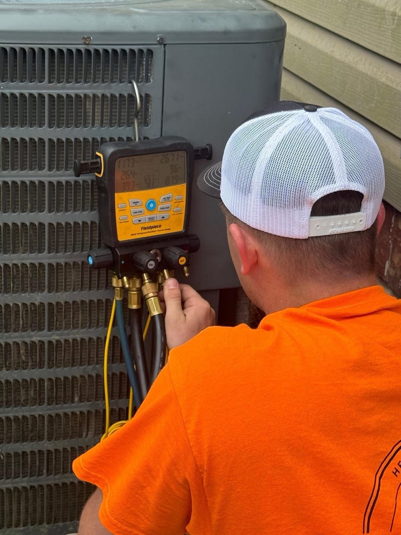 Electrician using a multimeter to inspect an air conditioner unit.