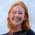 A close up of a woman with red hair smiling.