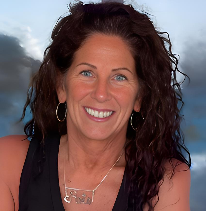 Smiling person with red hair, wearing a black shirt, outside.