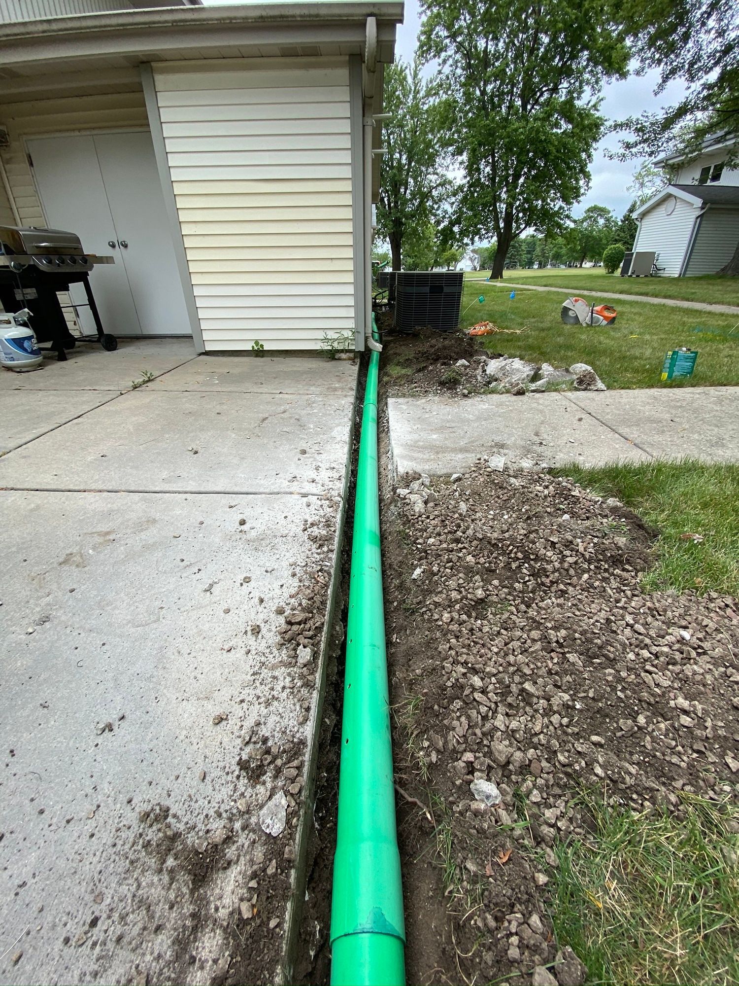 A green pipe is being installed on the side of a house.