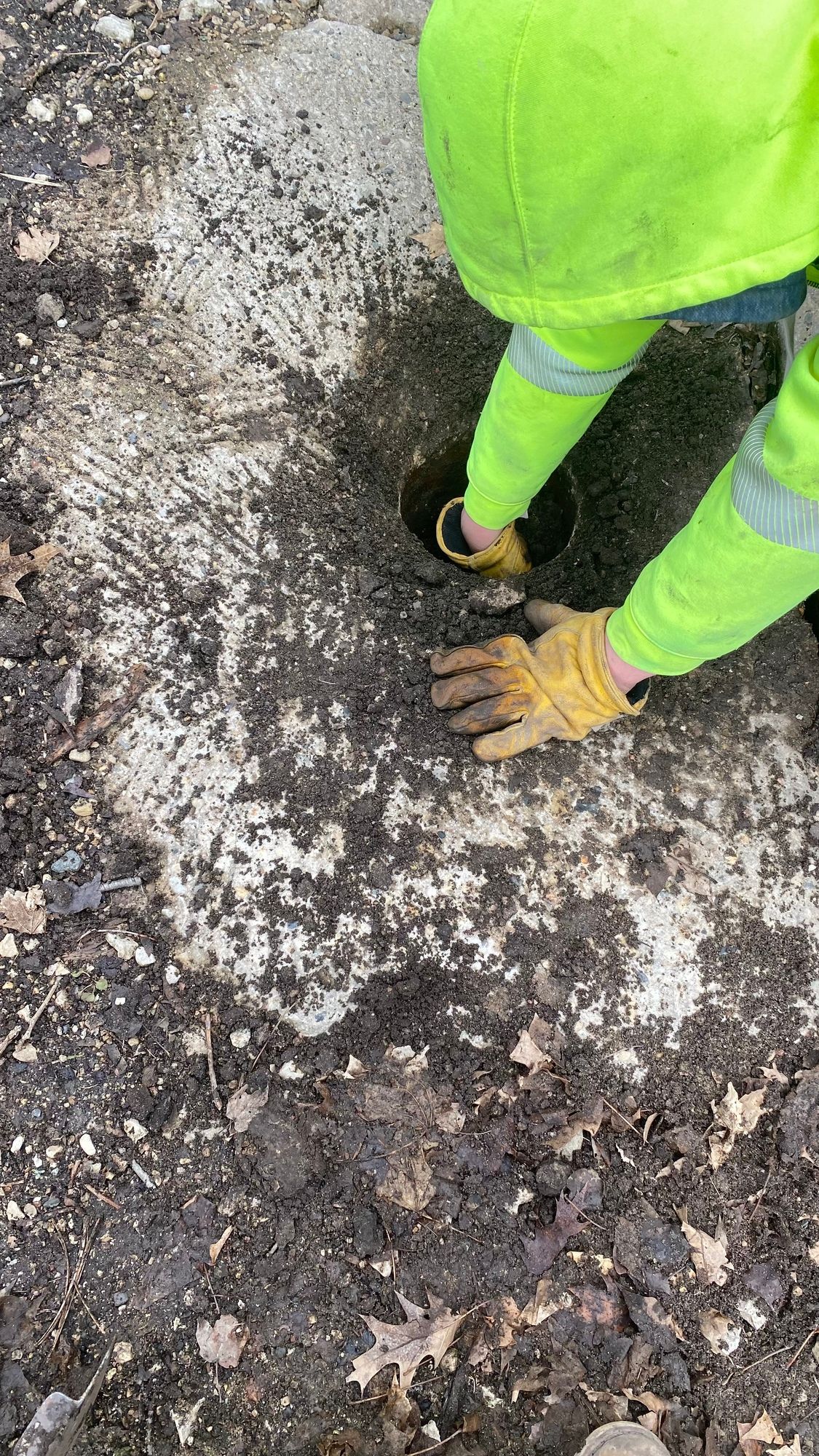 A person wearing gloves is standing on a dirt road.