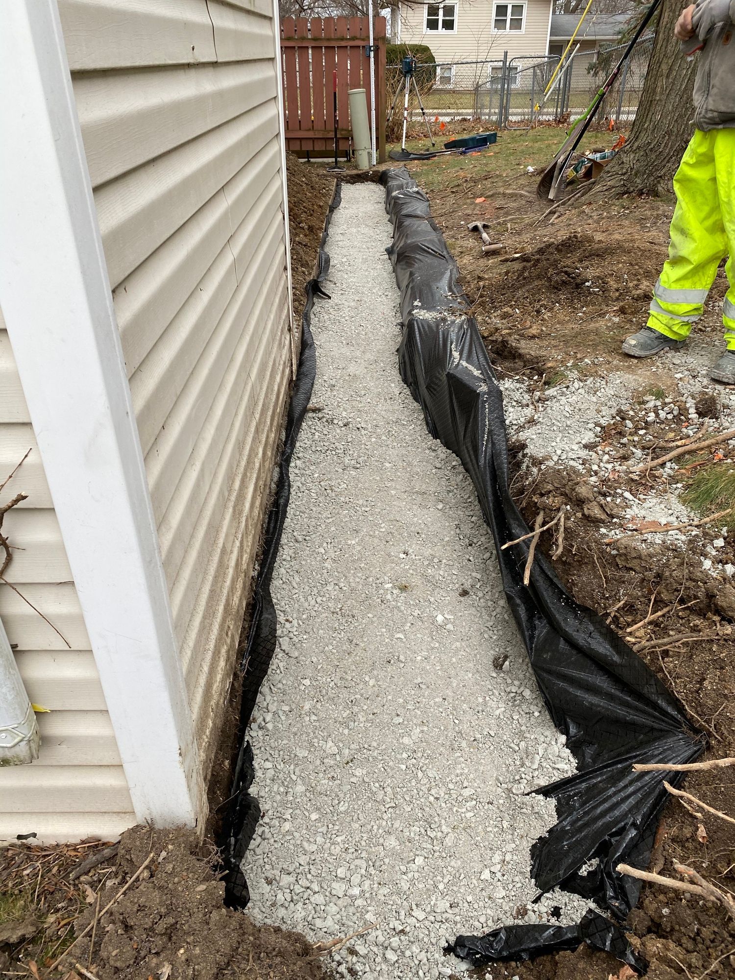 A man is digging a hole in the ground next to a house.