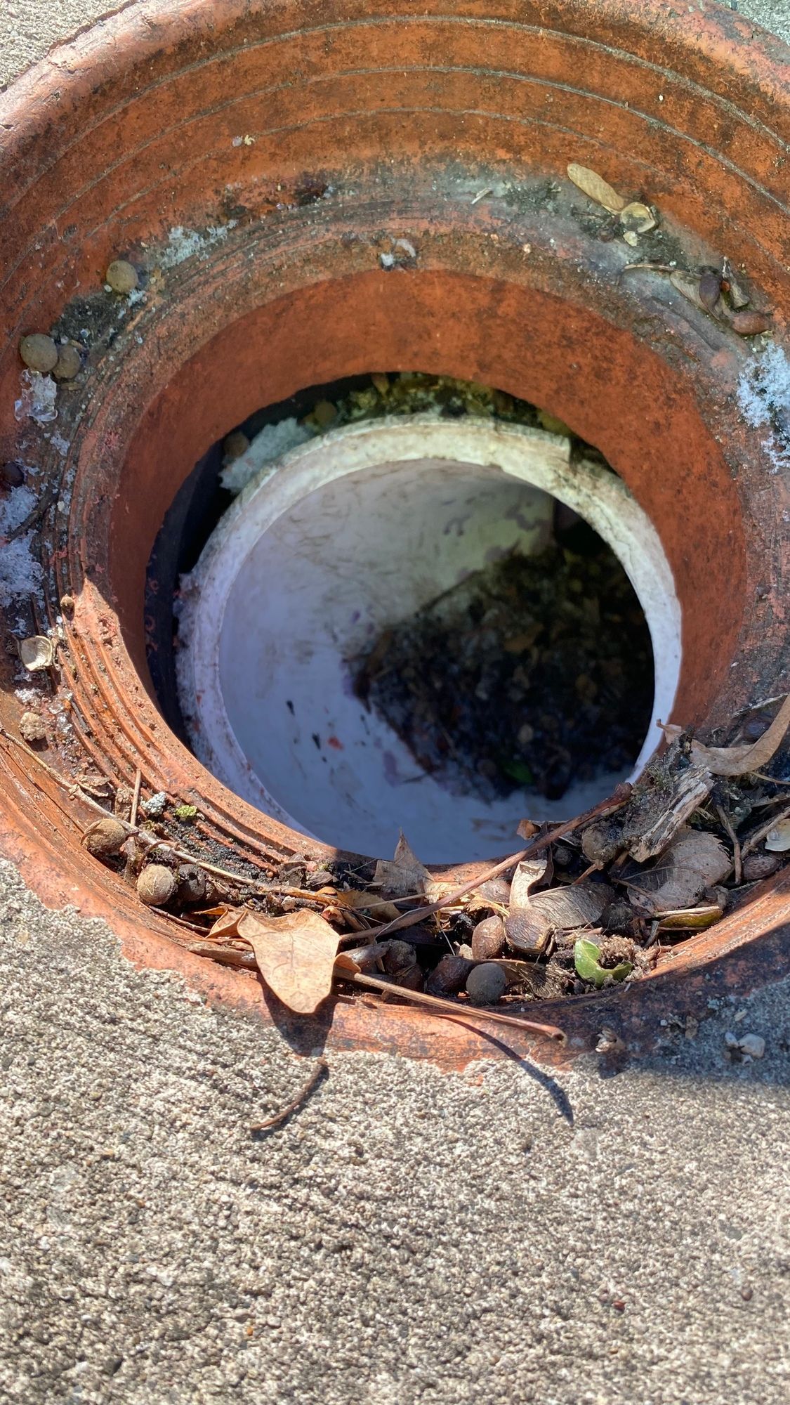 A close up of a hole in a brick pot on the ground.