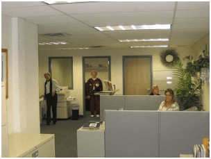 A man in a tuxedo stands behind a cubicle in an office – USA - Regal Construction Inc.
