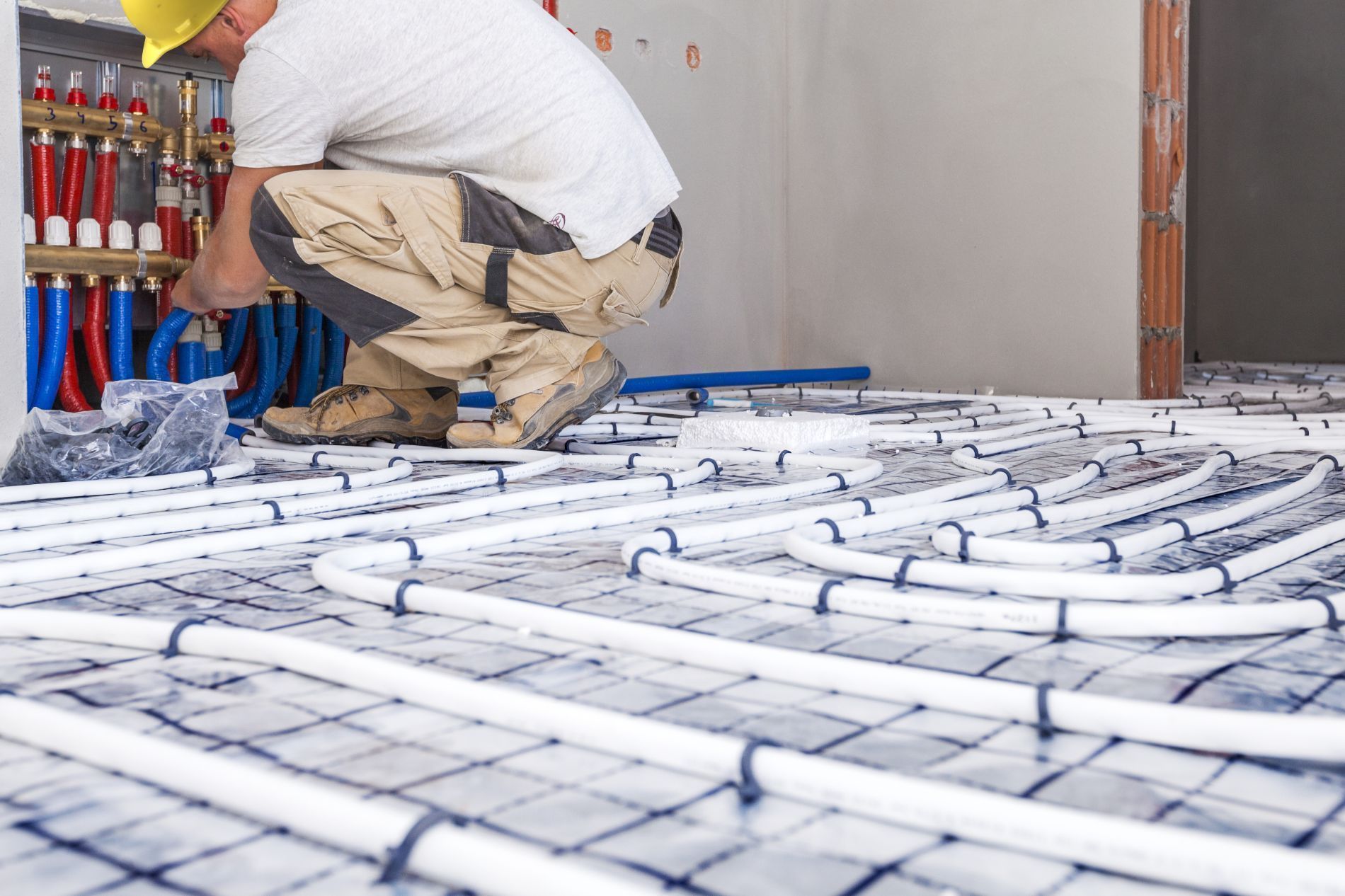 A man is installing underfloor heating pipes on the floor – USA - Regal Construction Inc.