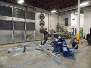 A group of men are working on a metal structure in a factory – USA - Regal Construction Inc.