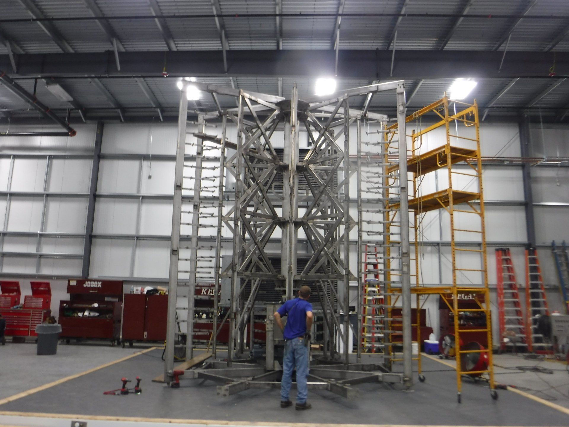 A man is standing in front of a large metal structure in a warehouse – USA - Regal Construction Inc.