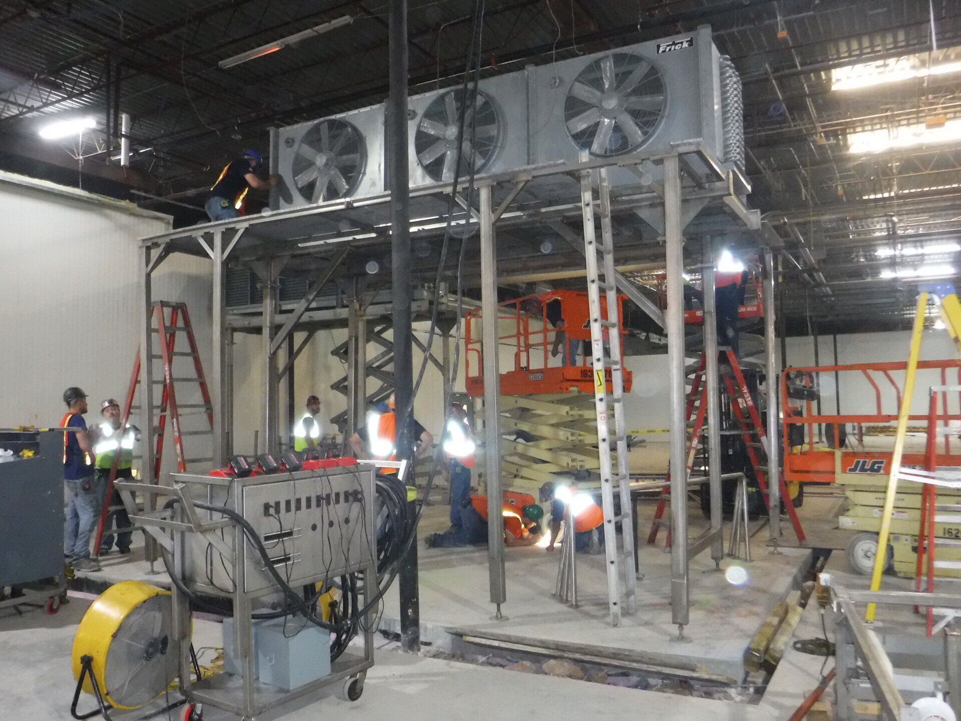 A group of people are working on a machine in a warehouse – USA - Regal Construction Inc.