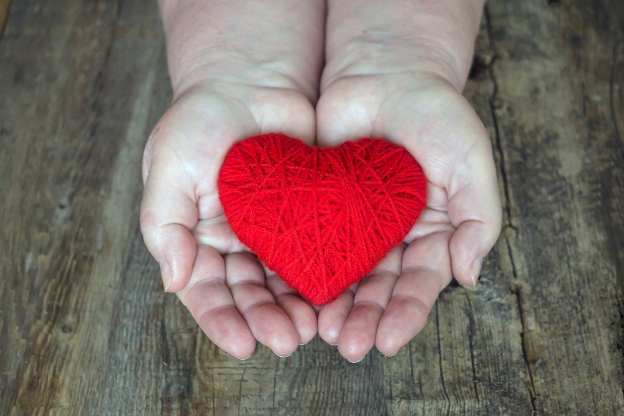 hands holding heart made of yarn. symbol of handcrafted care