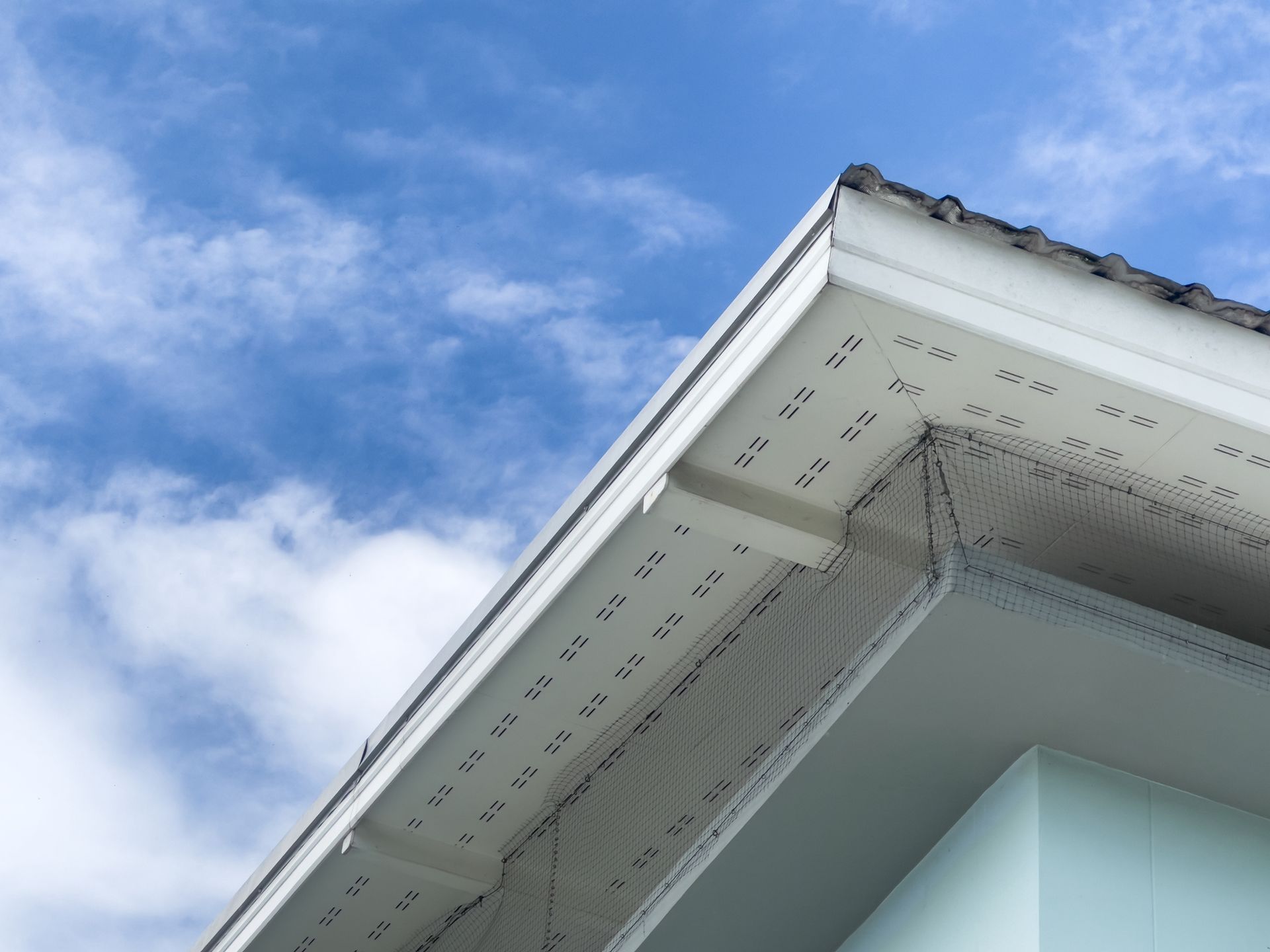 Looking up at the roof of a house with a blue sky in the background.