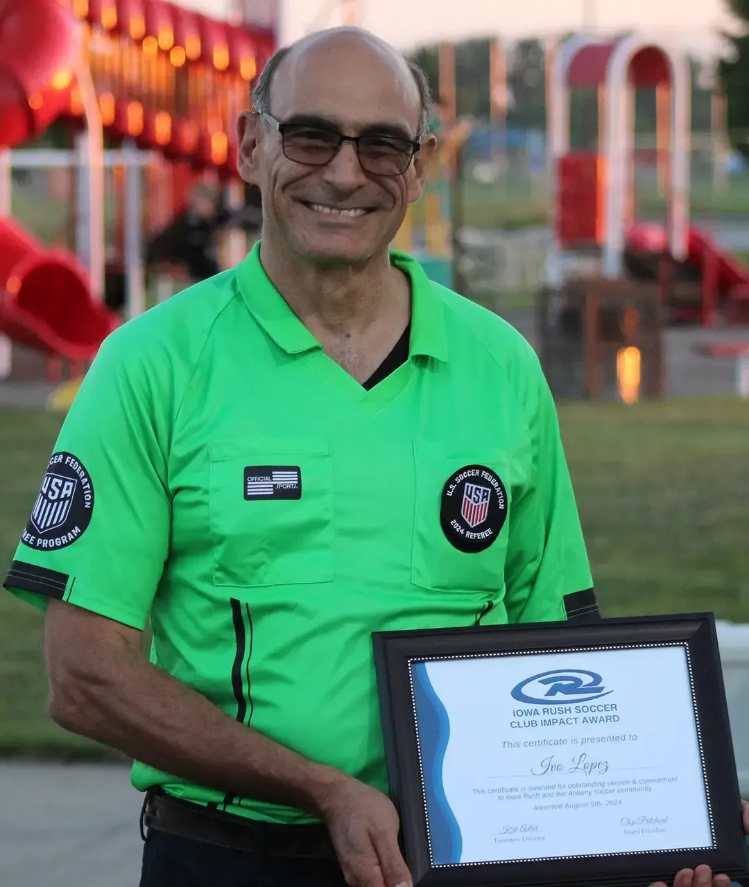 A soccer referee standing with a certificate