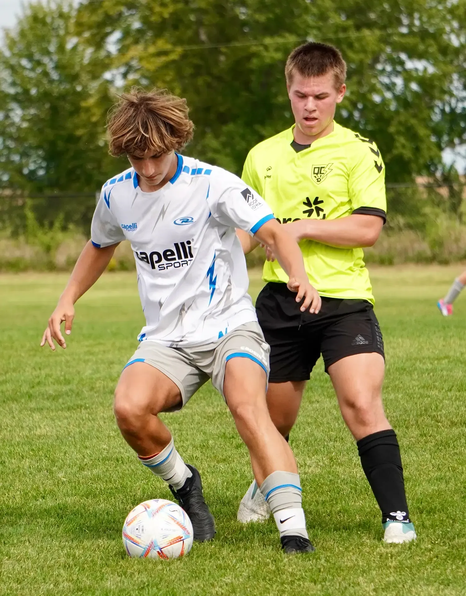 Two young men are playing soccer on a field.