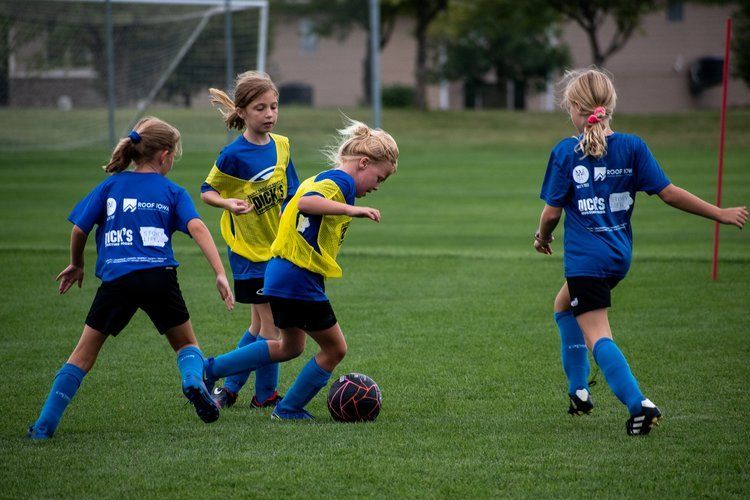 A group of young girls are playing soccer on a field.