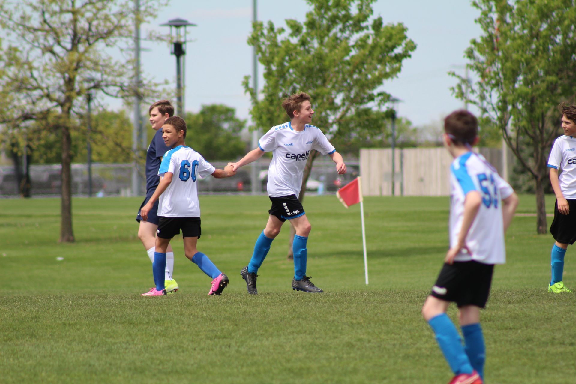 A group of young boys are playing soccer on a field high fiving