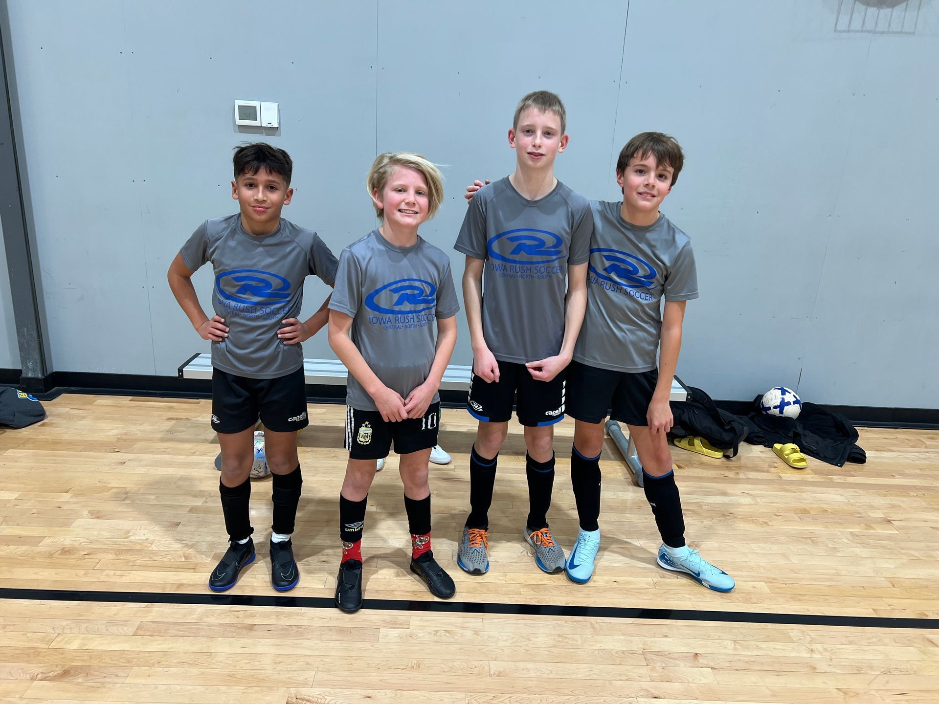 A group of young futsal players are posing for a picture in a gym.
