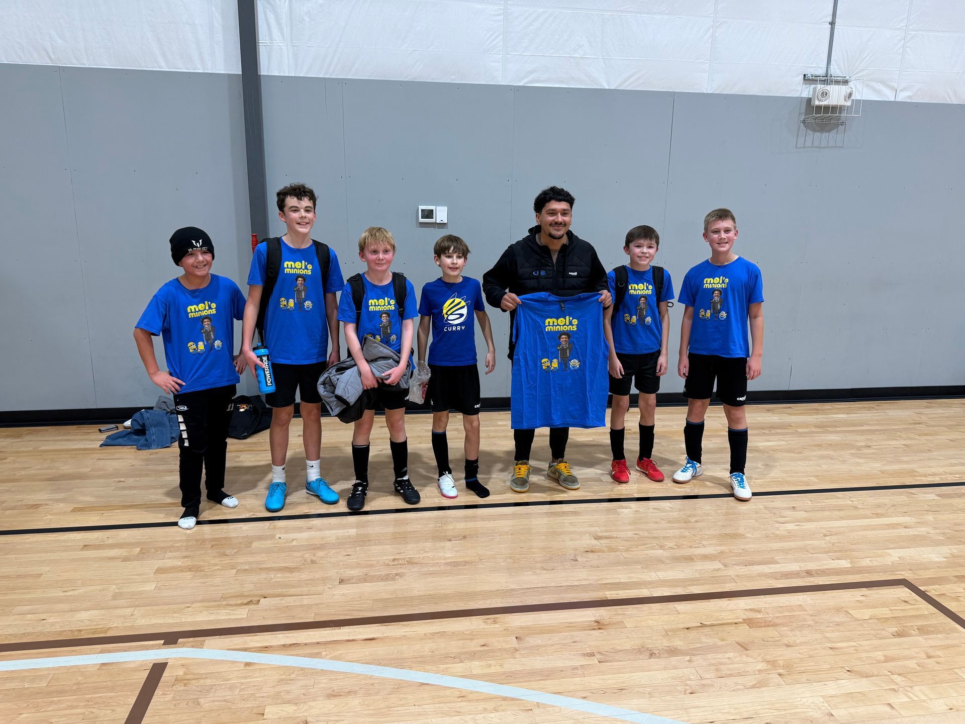 A group of young boys are posing for a picture in a gym.