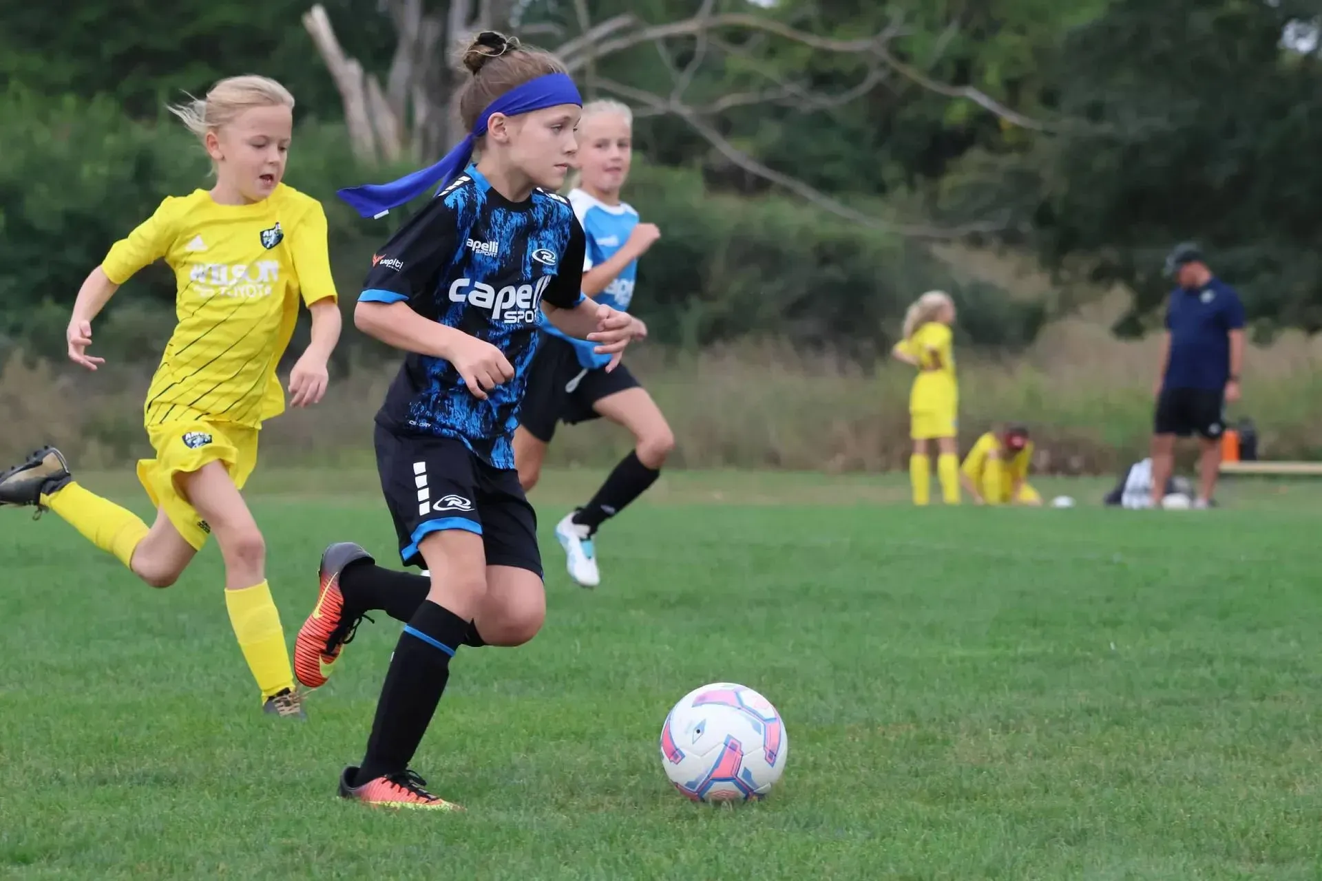 A group of young girls are playing soccer on a field.
