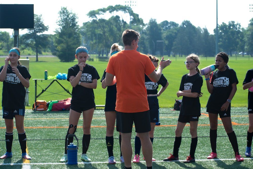 Soccer players in black shirts lined up listening to the coach