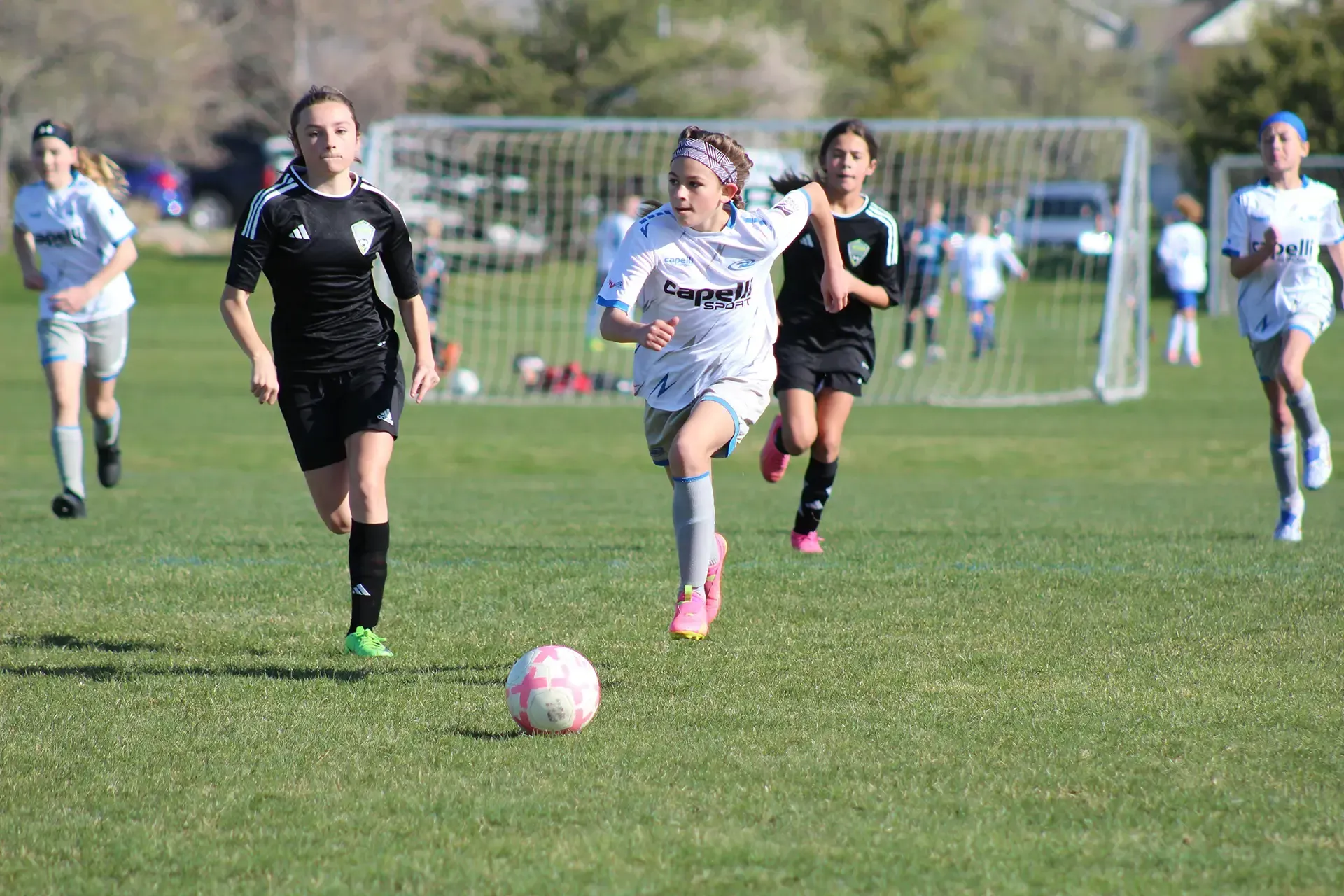 A group of young girls are playing soccer on a field.