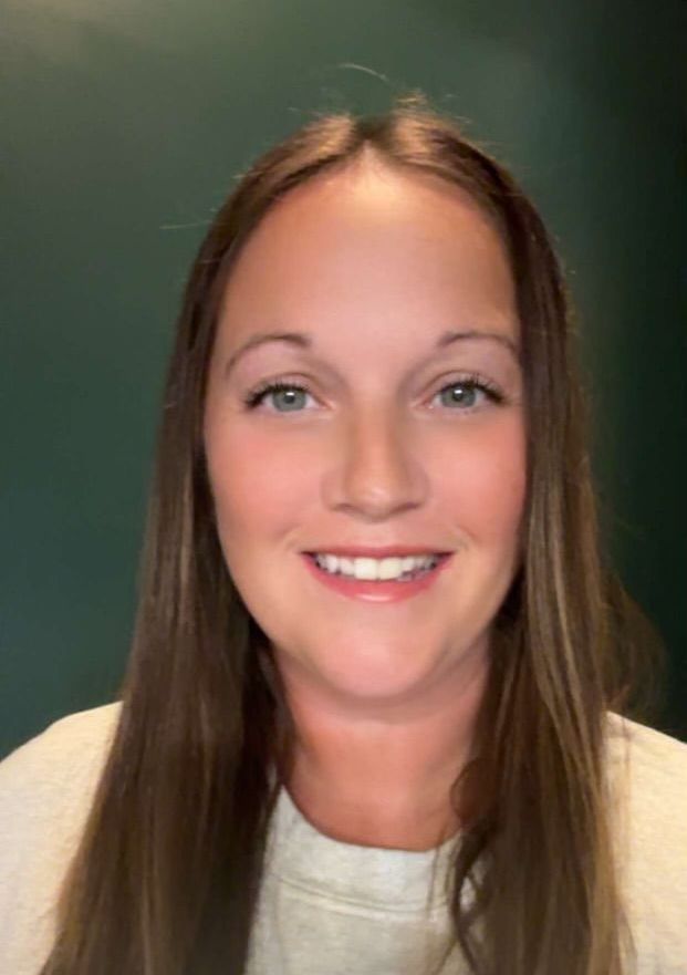 A woman with long brown hair is smiling for the camera.