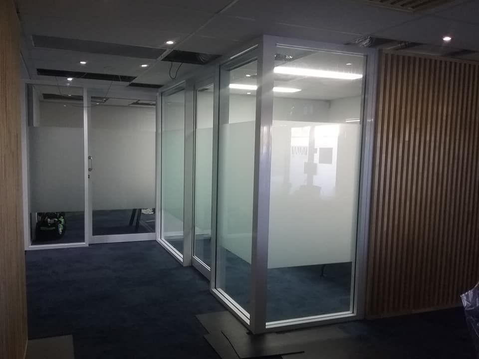 Office space with glass and frosted glass partitions and wooden paneling.
