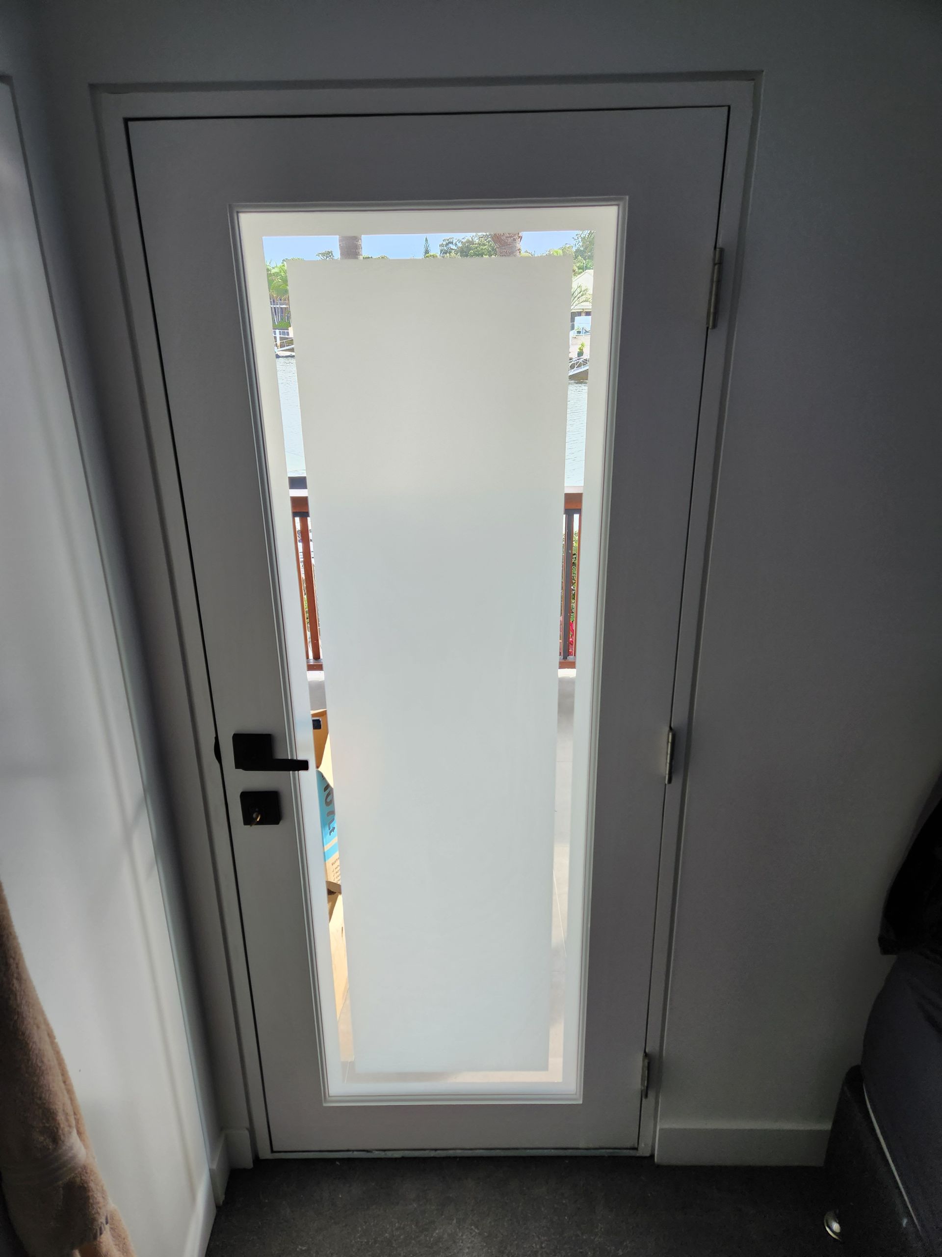 White door with frosted glass panel, black handle, in white doorway.