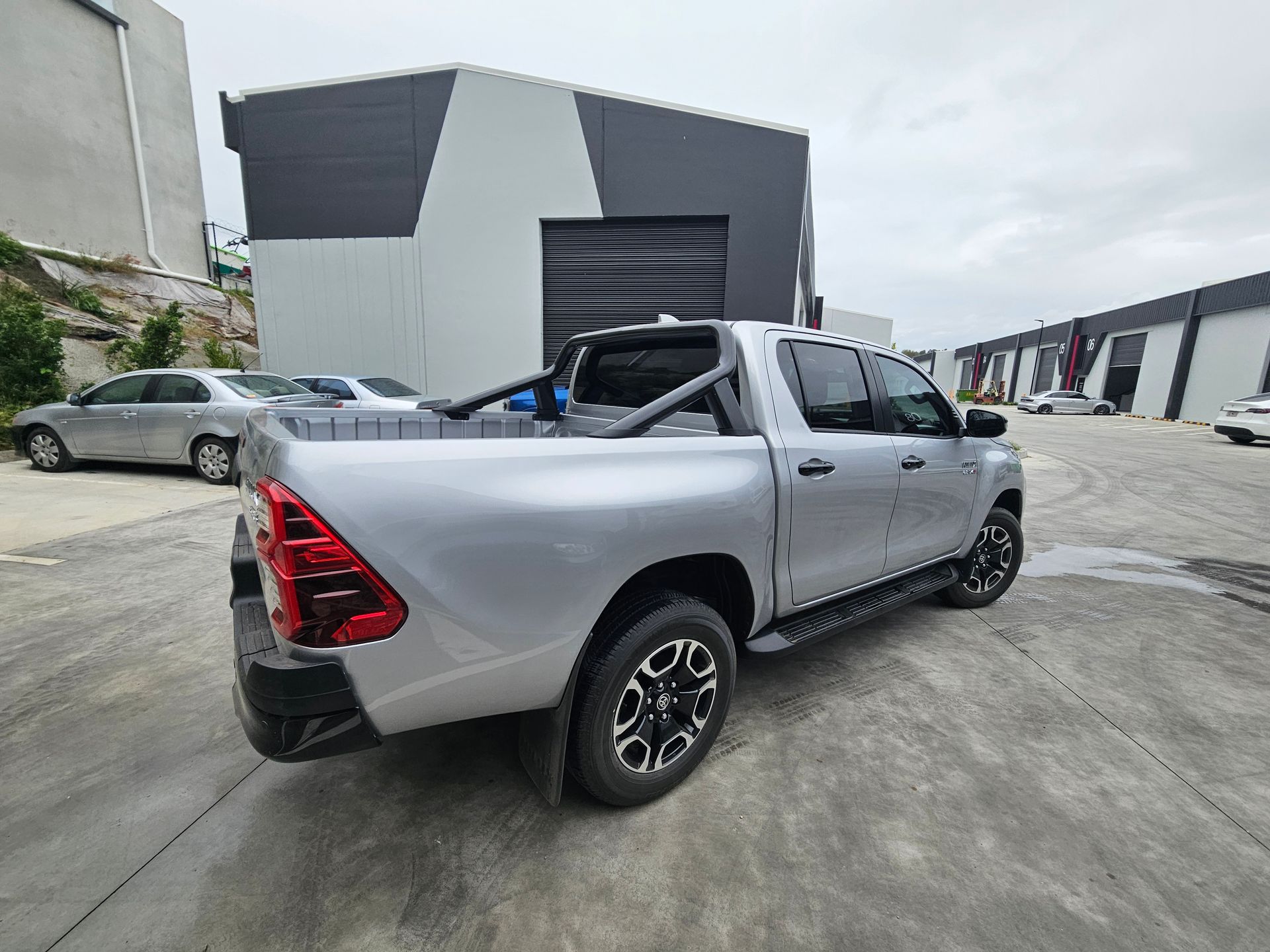 A white truck with the windshield removed is parked in front of a building.