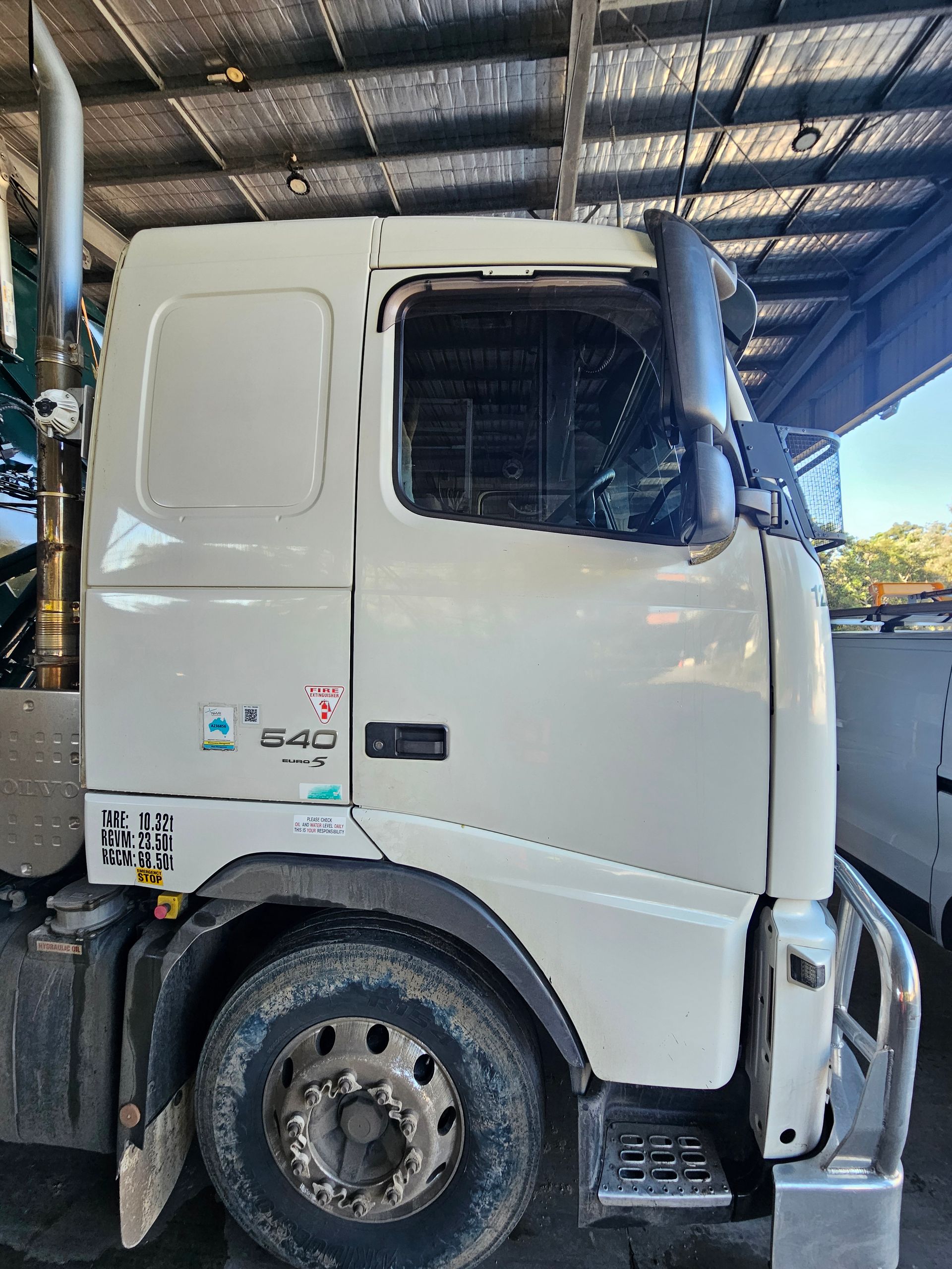 White Volvo semi-truck cab with the number 540 on it; parked inside a shelter.