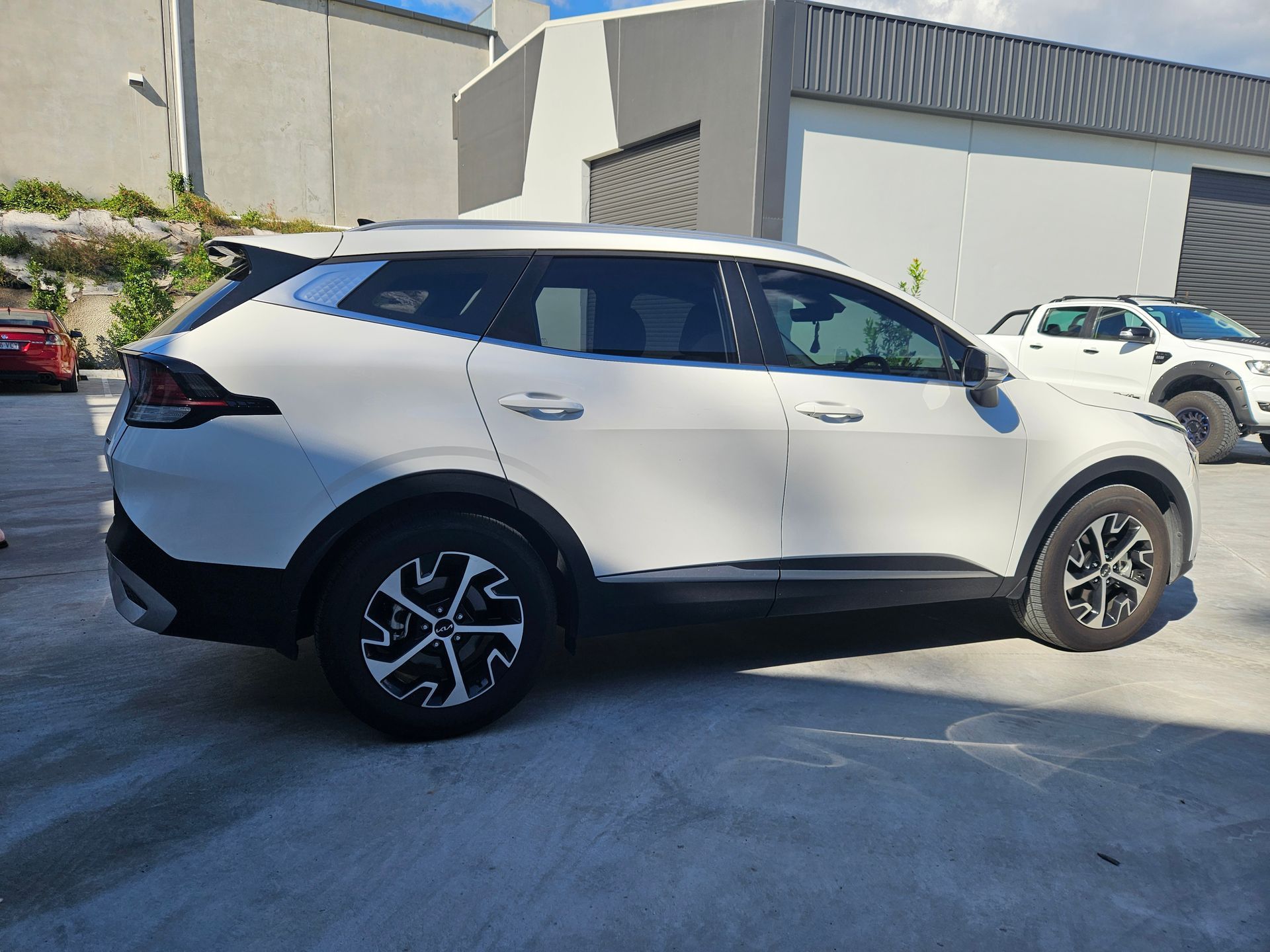 White Kia SUV parked outside a building.