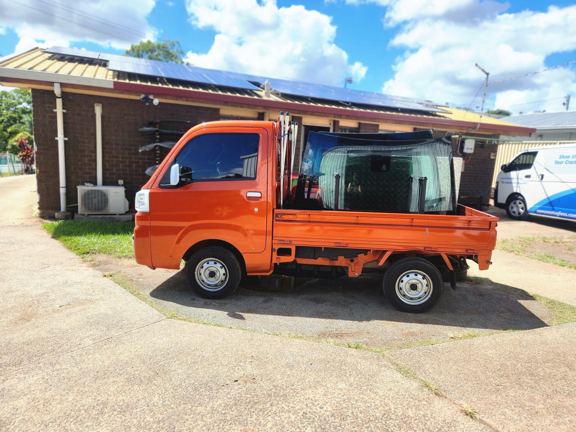 A small orange truck is parked in front of a building.
