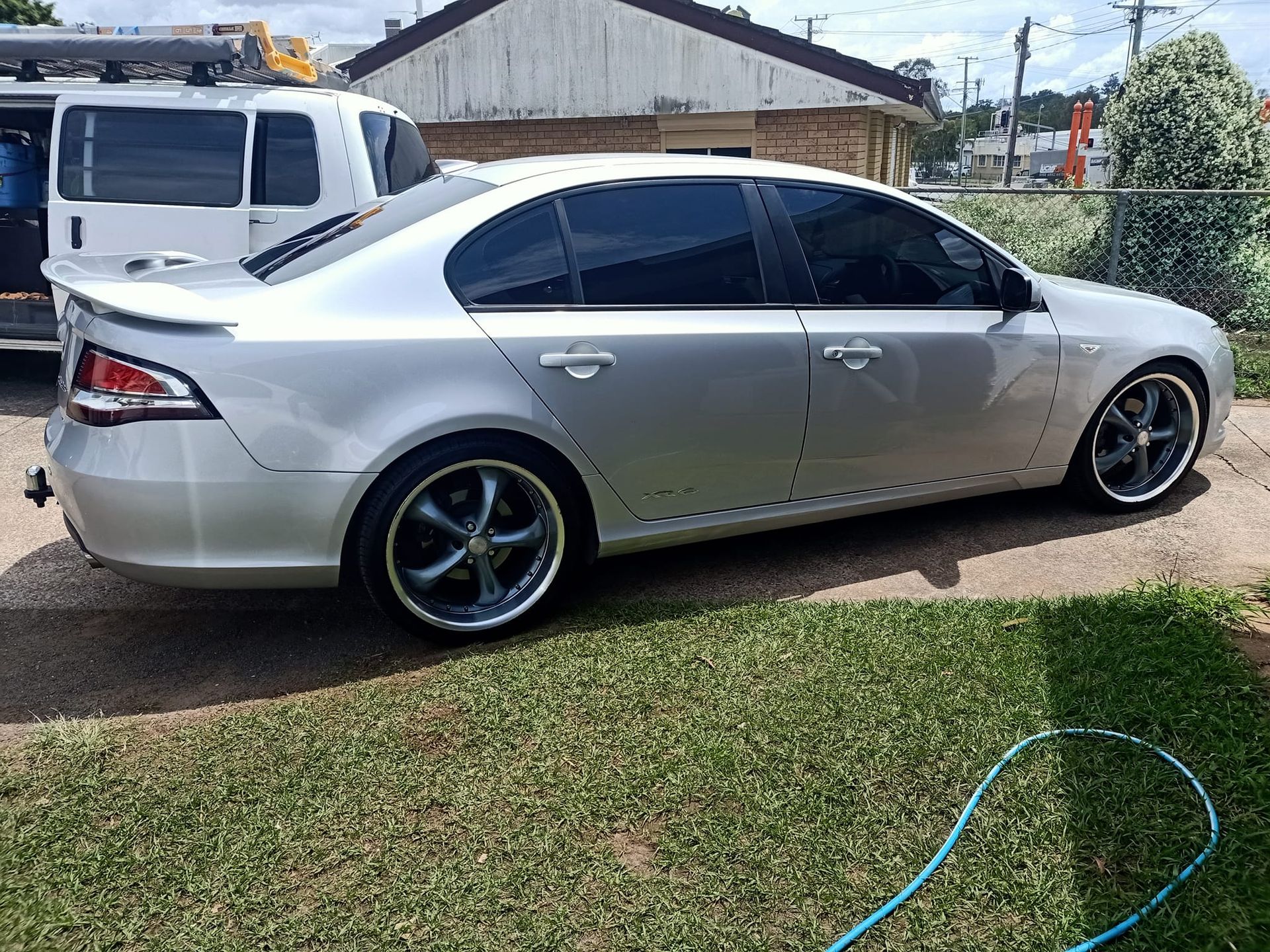 A silver car is parked in a driveway next to a white van.