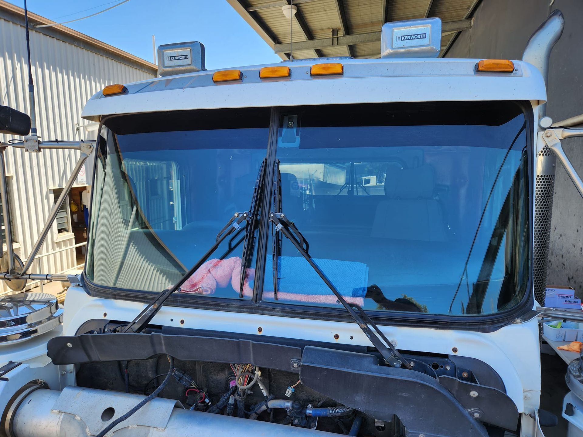 White semi-truck cab with tinted windshield, wiper blades, and amber roof lights.