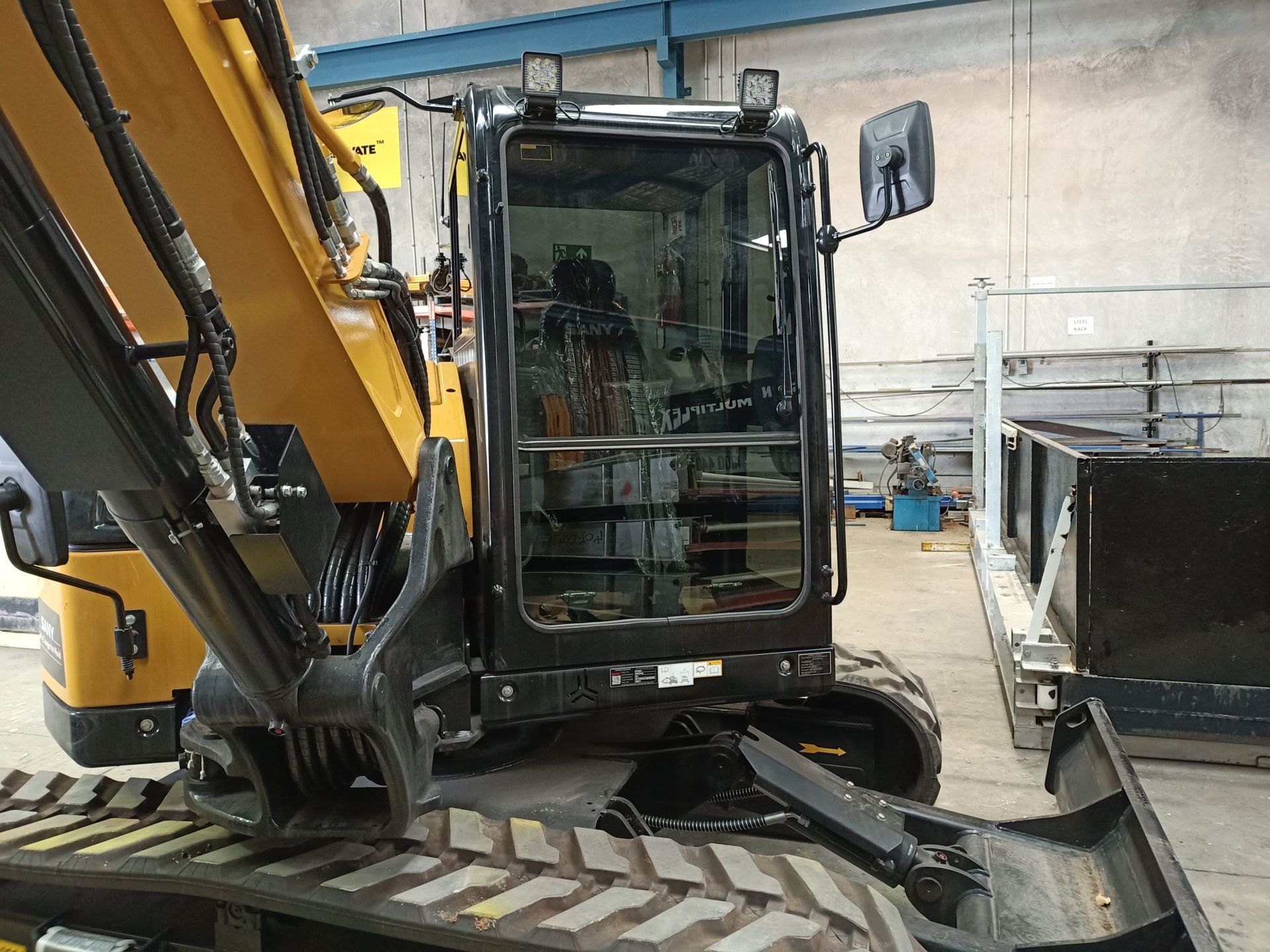 Yellow and black excavator cab in a workshop.