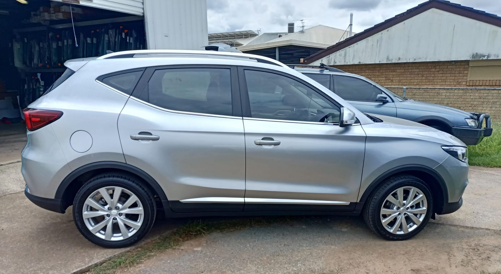 A silver car is parked in a driveway next to a garage.
