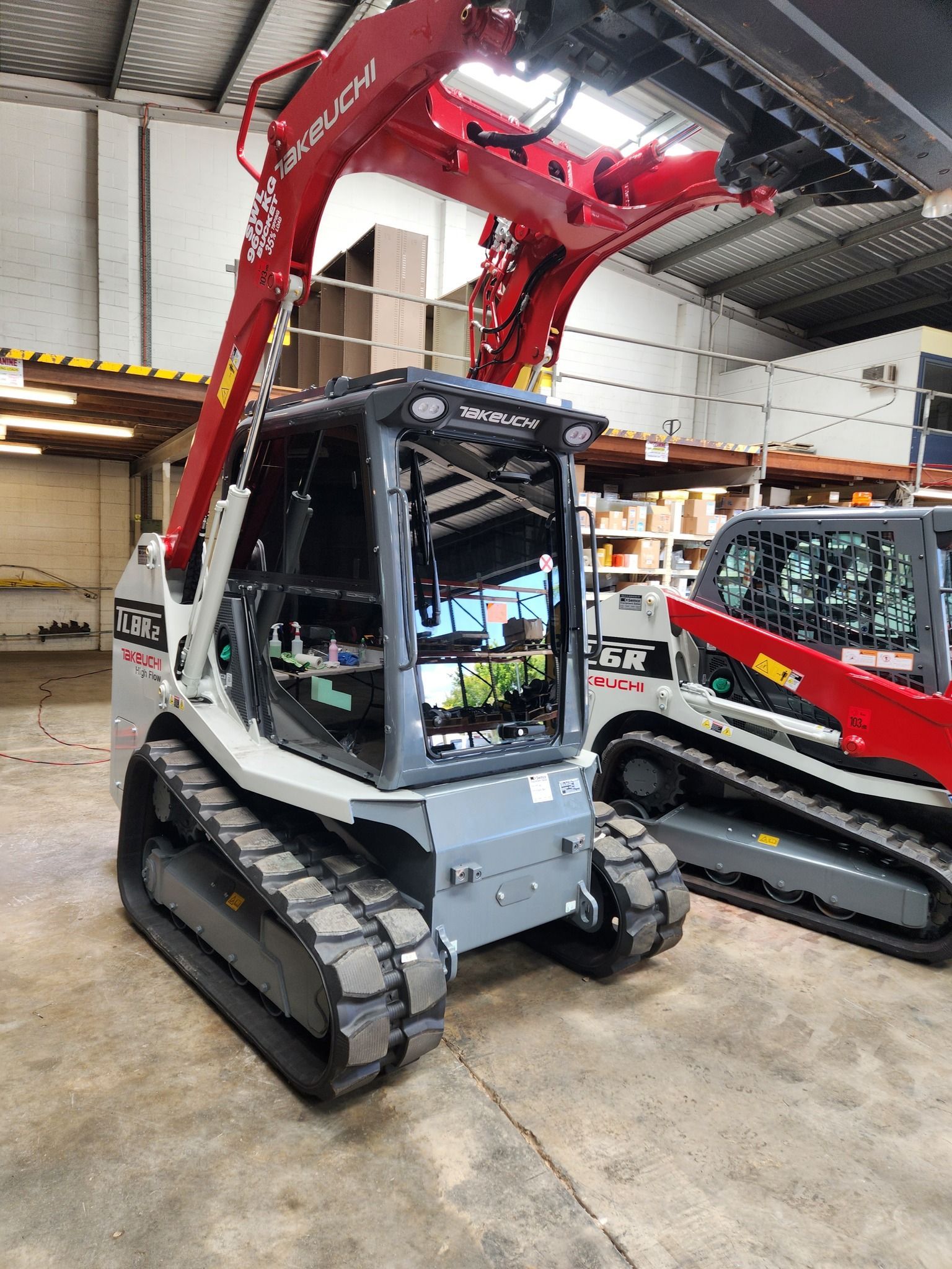 A yellow and black excavator is parked in a warehouse.