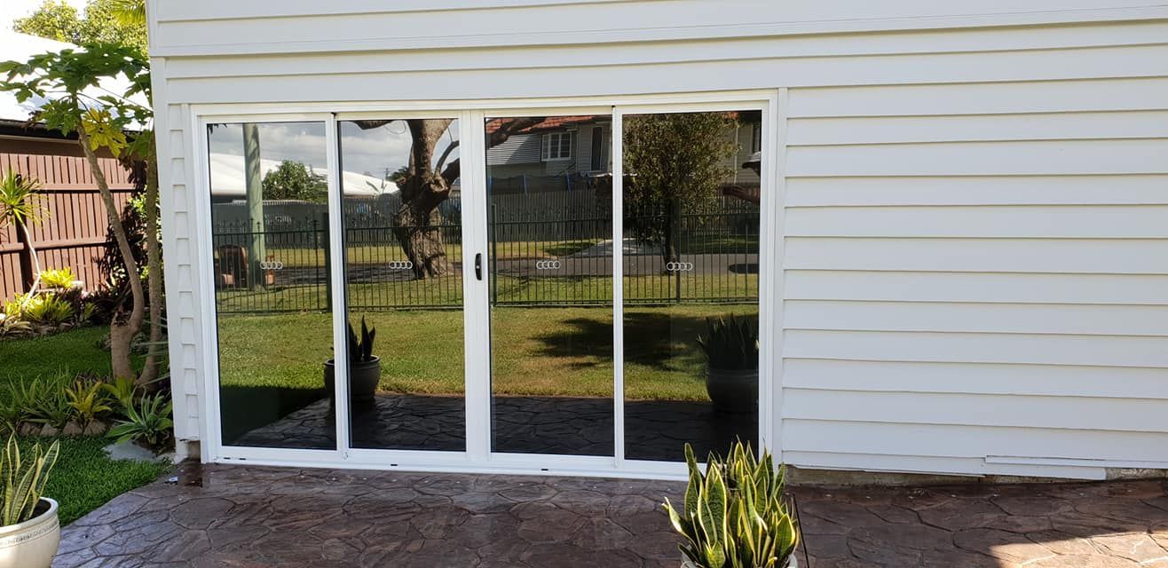 White building with reflective glass doors overlooking a backyard.