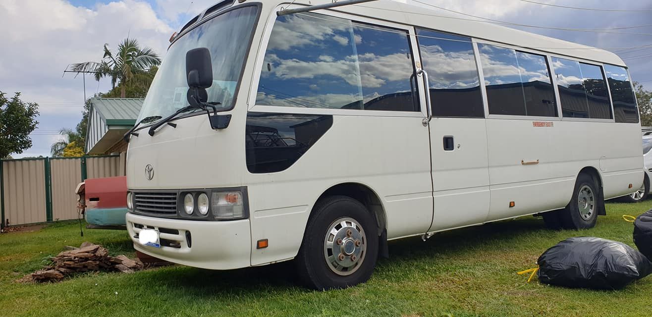 A yellow and black tractor is parked under a roof in a parking lot.
