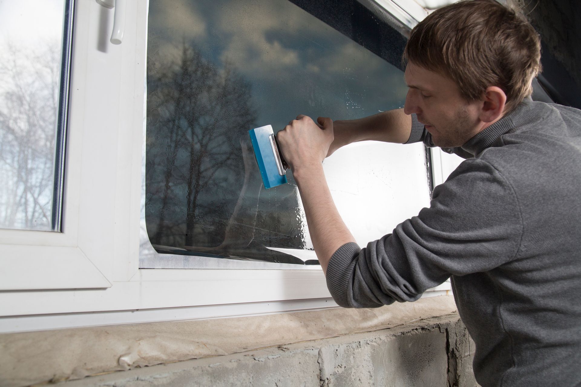 A man is installing a window film in the office.