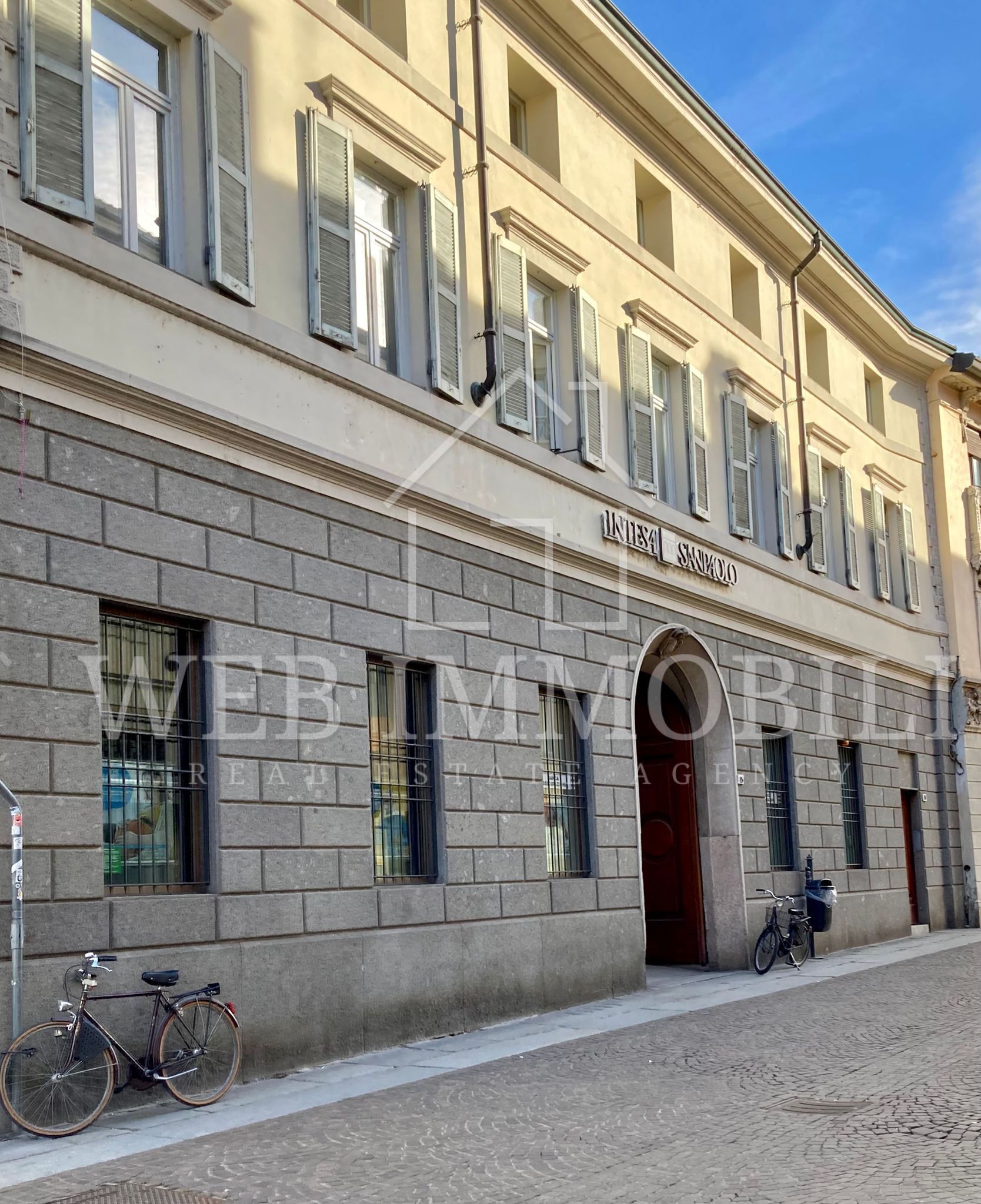 Edificio in pietra con finestre chiuse, porta scura e biciclette.