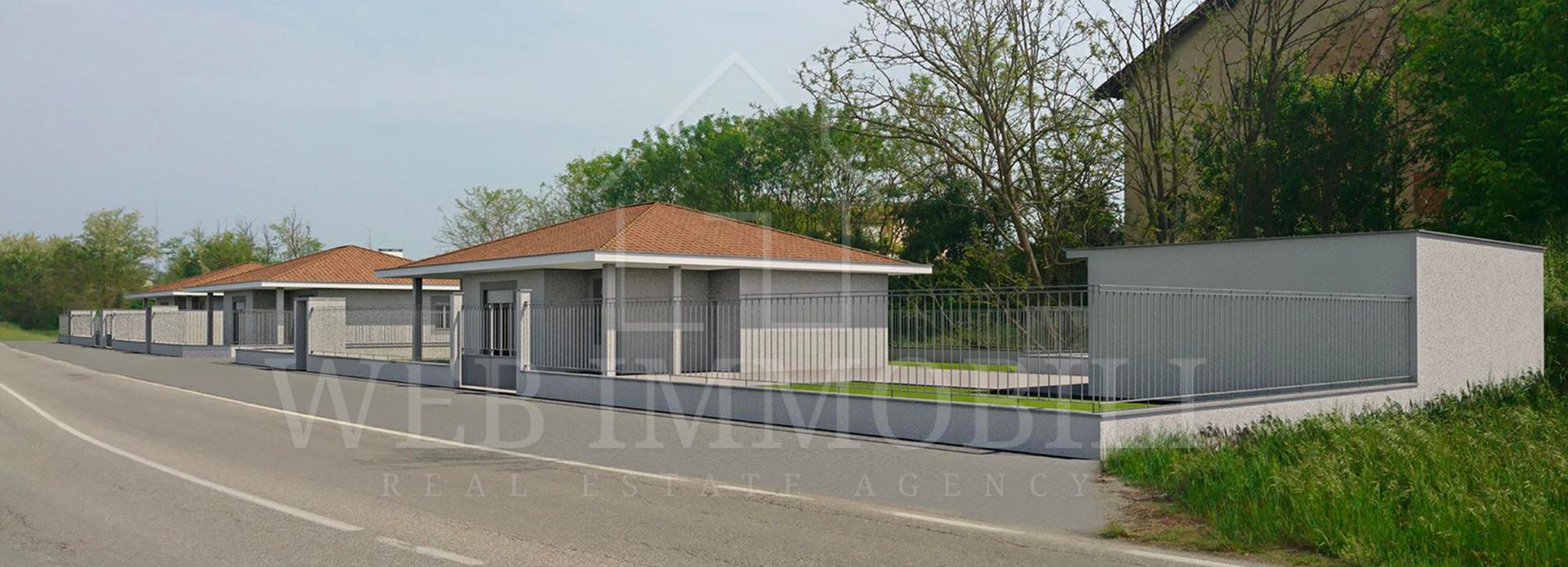 Edifici con tetti di tegole arancioni, lungo una strada e circondati dal verde.